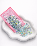 Pink container of rhinestones on a white dish with 'Gempires' branding.