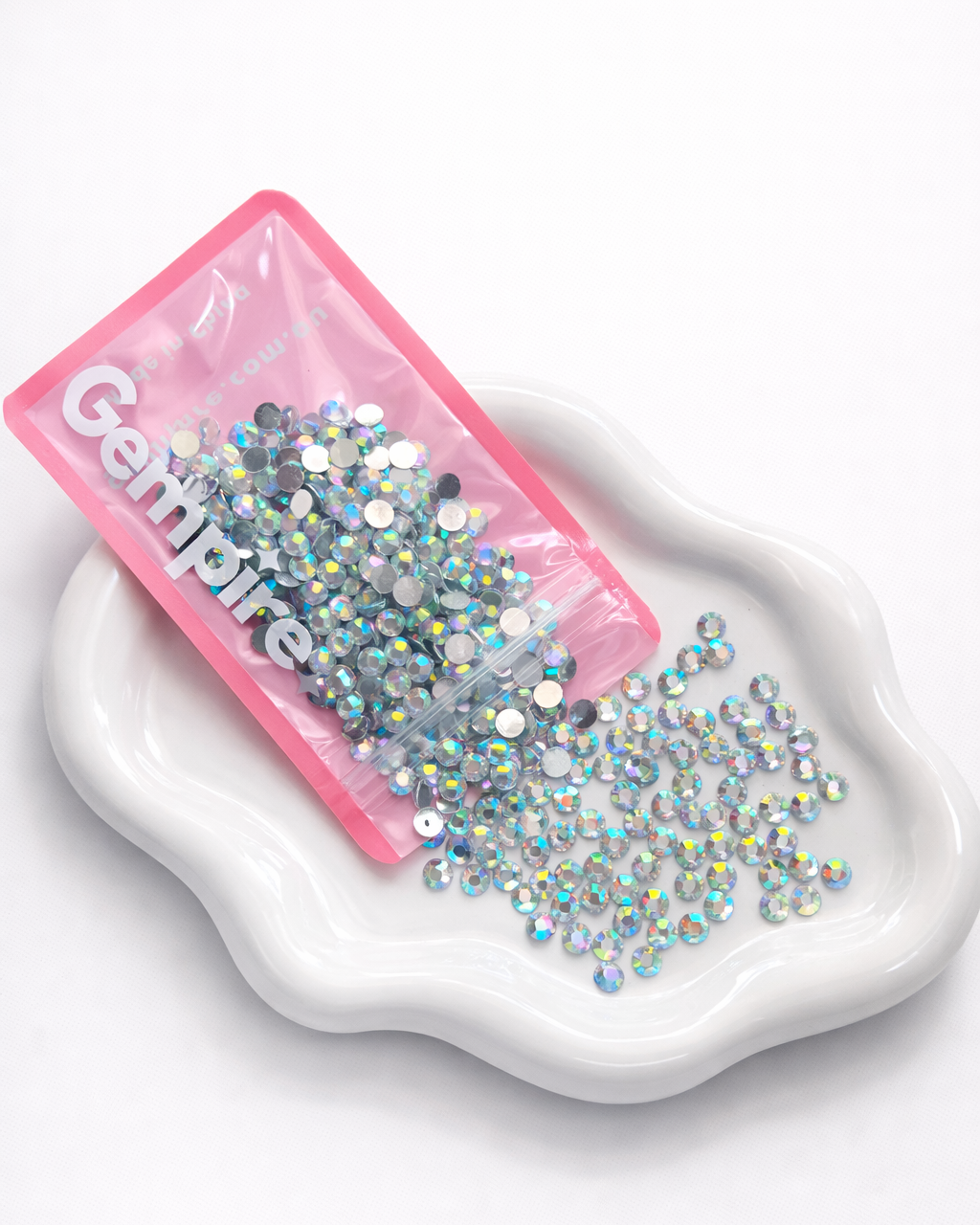 Pink container of rhinestones on a white dish with 'Gempires' branding.